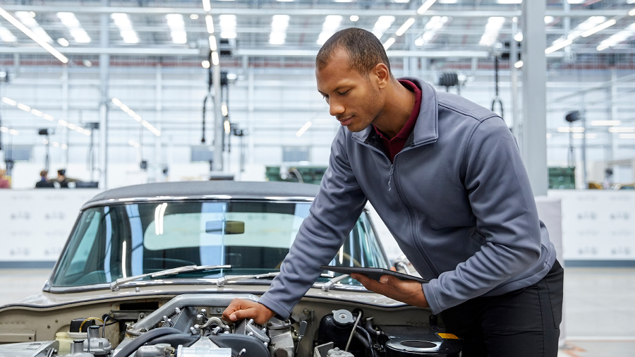 Ein Autoingenieur prüft die Teile eines Autos mit offener Motorhaube und hält ein ASUS ExpertBook B3 Notebook in der Hand.