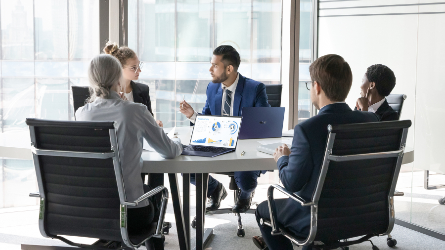 Un grupo de empleados se encuentra en una sala de reuniones con laptops ASUS ExpertBook sobre el escritorio.