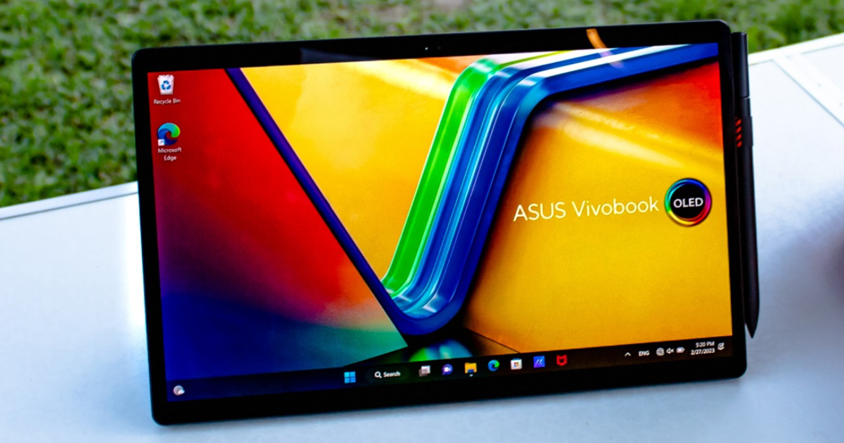 ASUS Vivobook 13 Slate OLED convertible laptop in a horizontal stand mode on a camping table with grass in the background
