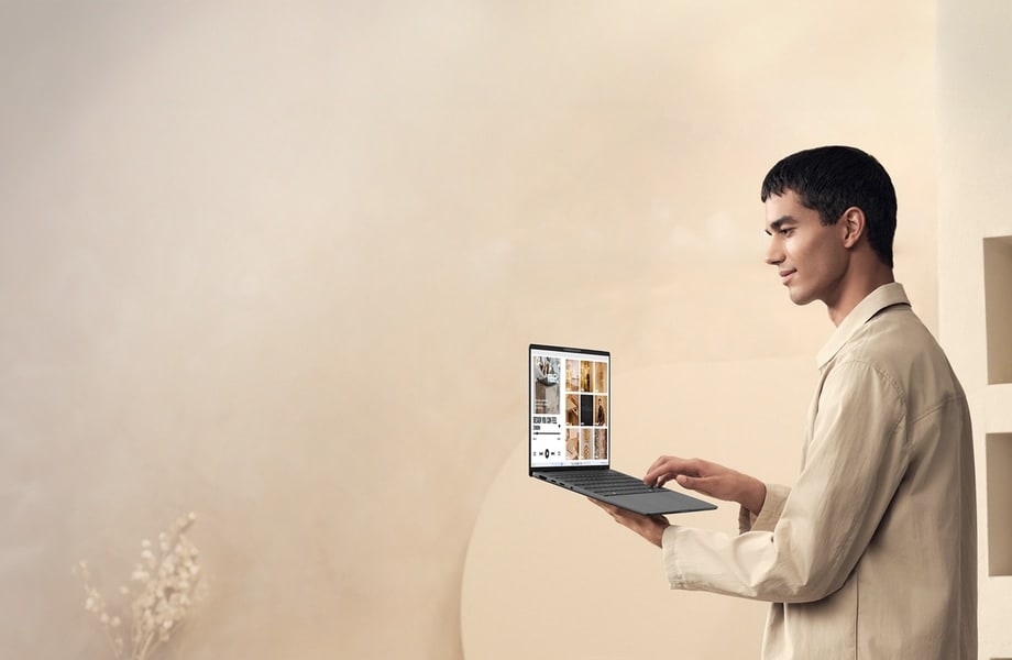 Mężczyzna trzymający szarego laptopa Zenbook A14 z pokrywą otwartą pod kątem 100 stopni.