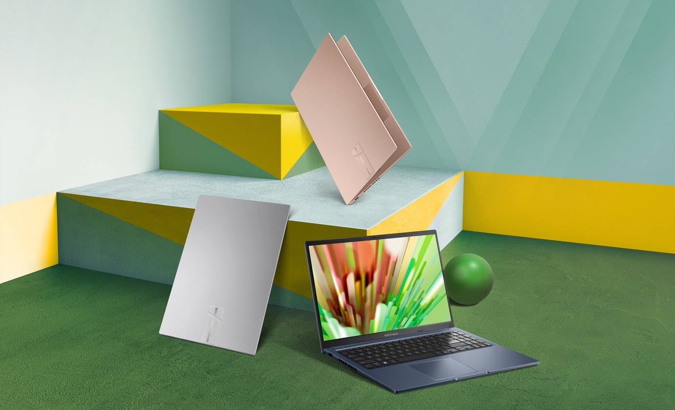 Trzy laptopy Vivobook 15 w kolorach Cool Silver, Terra Cotta i Quiet Blue pokazane wokół kolorowych bloków. Jeden z laptopów ma otwartą pokrywę pod szerokim kątem i wyświetla żywy obraz, a dwa laptopy mają zamkniętą pokrywę. 