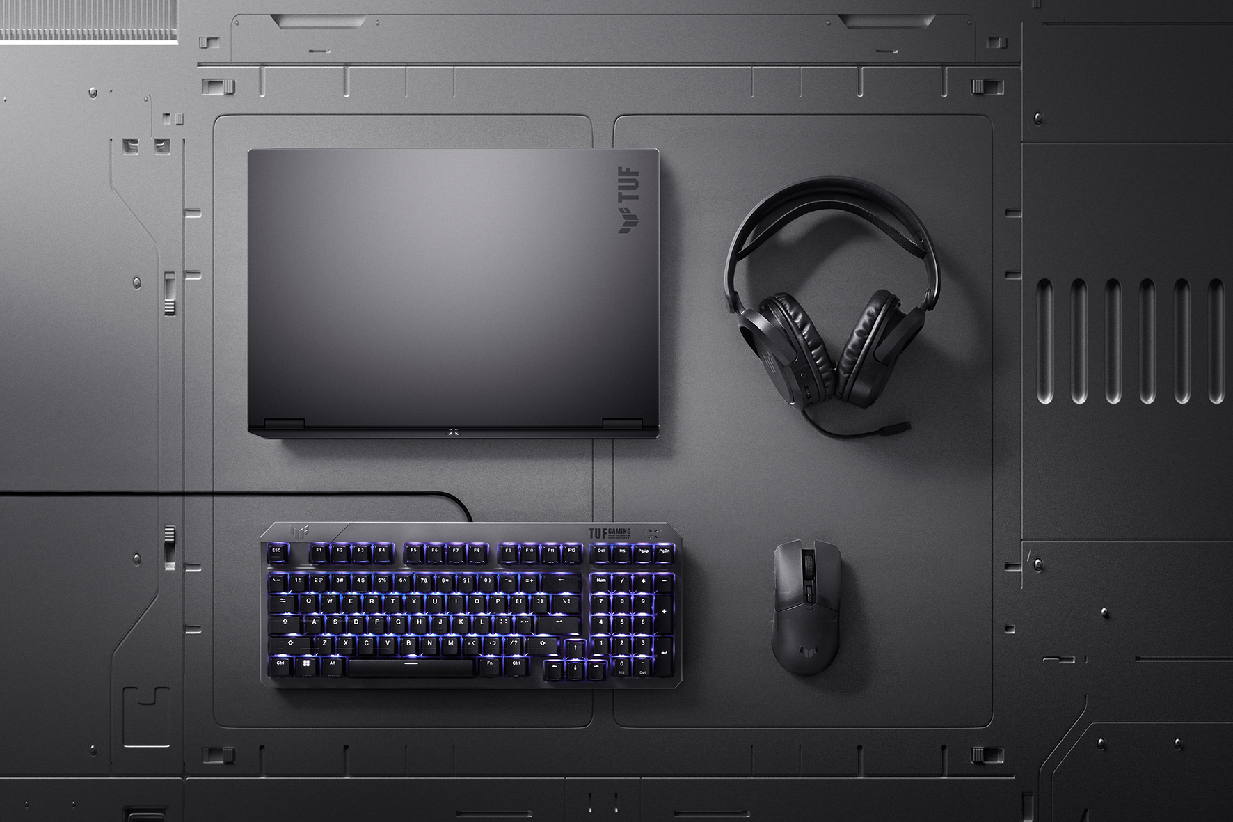 A TUF Gaming A16, headset, mouse, and keyboard arranged on a metallic background.