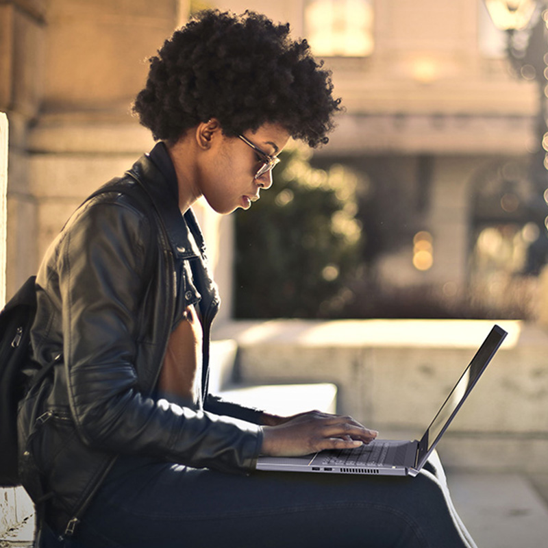 a young woman sitting on stairs outdoors using ASUS ProArt StudioBook 17 to create digital content