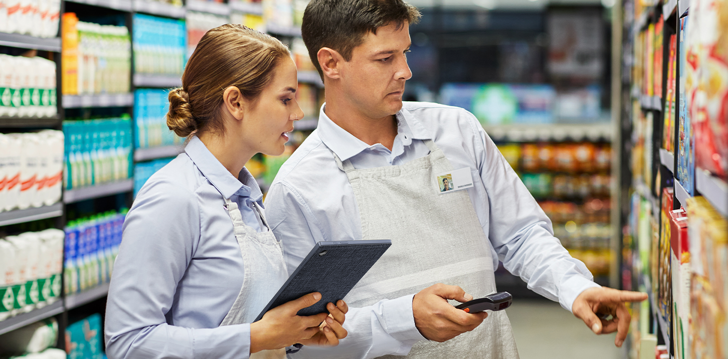 Deux employés de supermarché vérifient ensemble les produits en rayon, l'ordinateur portable détachable ASUS ExpertBook B3 à la main.