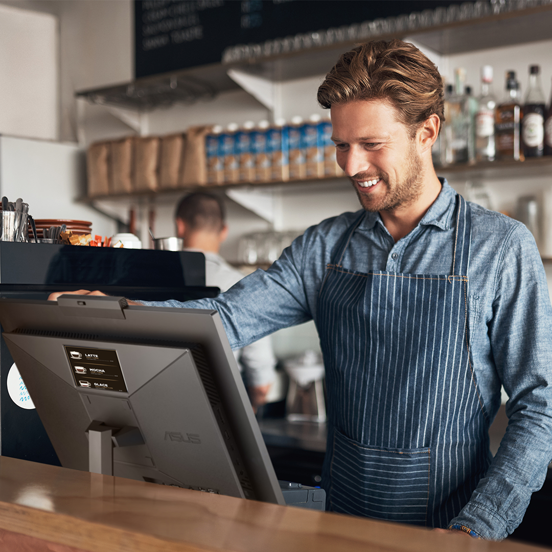 A coffee shop staff is using the ASUS ExpertCenter E5 AiO at the front desk.