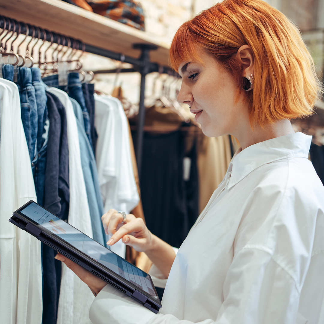 A clothing store employee is looking at the ASUS ExpertBook B5 Flip in tablet mode in the store.