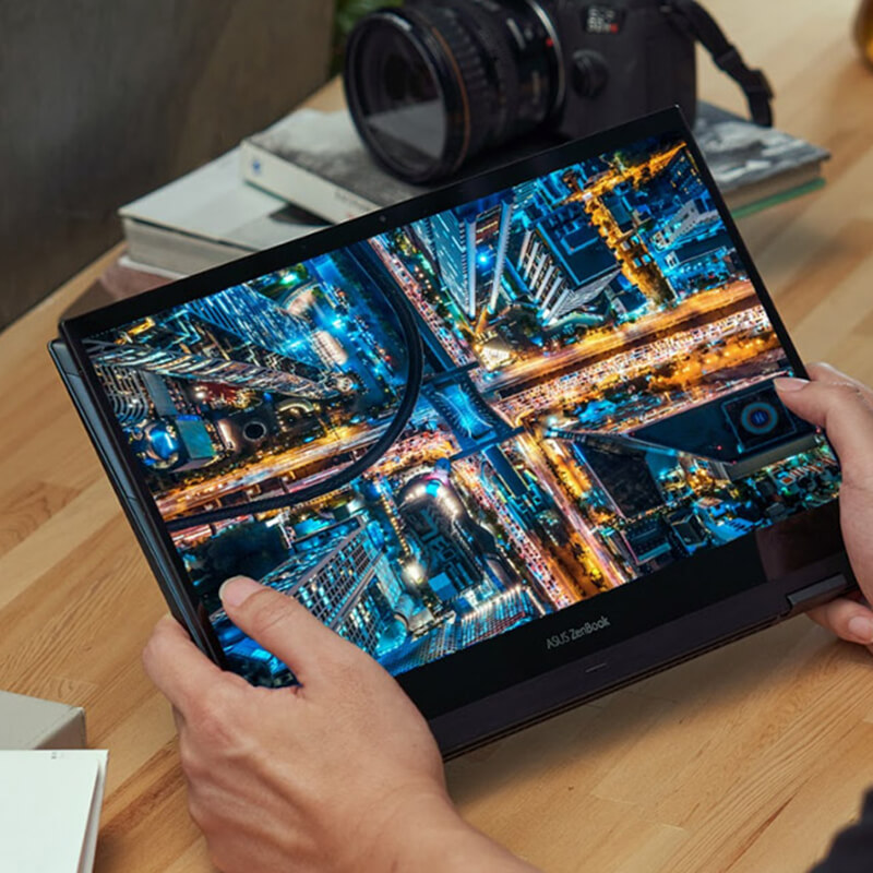 ASUS Zenbook Flip 13 OLED Intel® Evo™ convertible 2 en 1 portátil con pantalla OLED siendo utilizado en el modo Tablet para mostrar foto de alta resolución a color en el escritorio junto a una cámara.