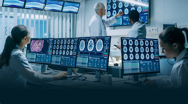 In the hospital lab, two doctors sit in front of a desktop with multiple displays to view medical imaging, such as X-ray and ultrasound images, while two other doctors discuss the content.