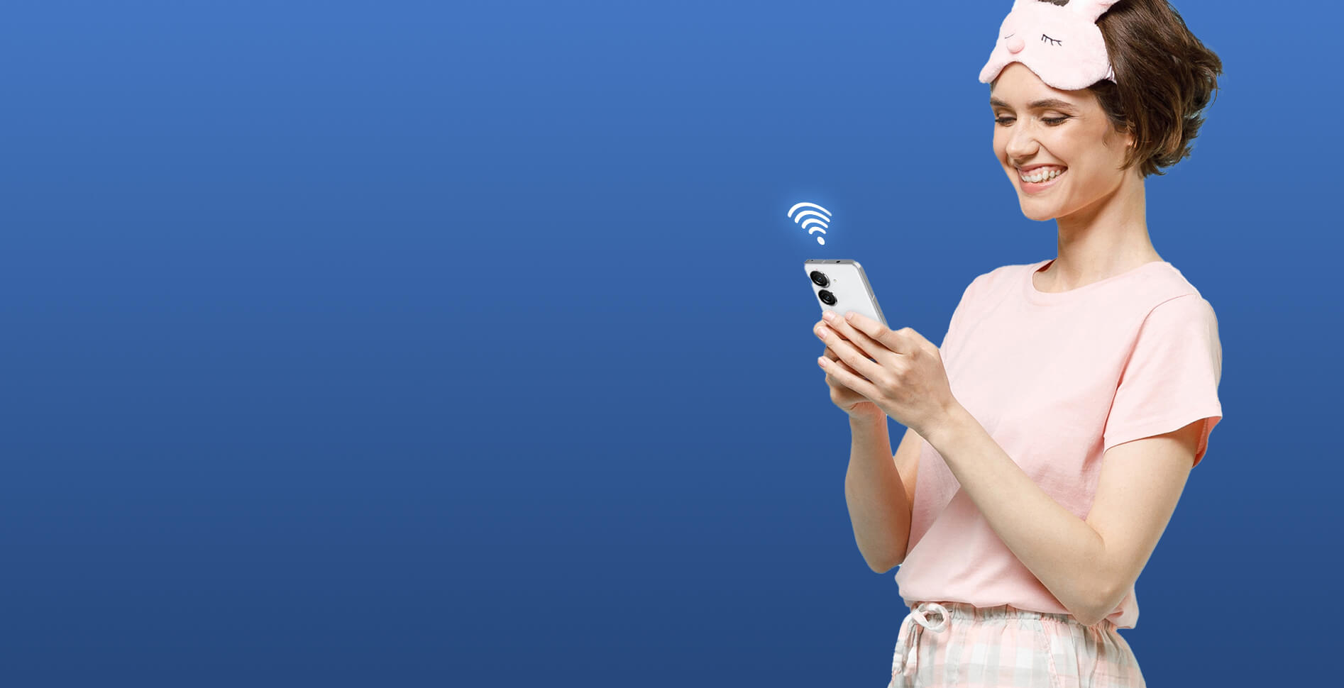 Kobieta w różowej piżamie trzyma telefon komórkowy z pełnym sygnałem WiFi, uśmiechając się, gdy cieszy się bezproblemowym roamingiem w domu.
