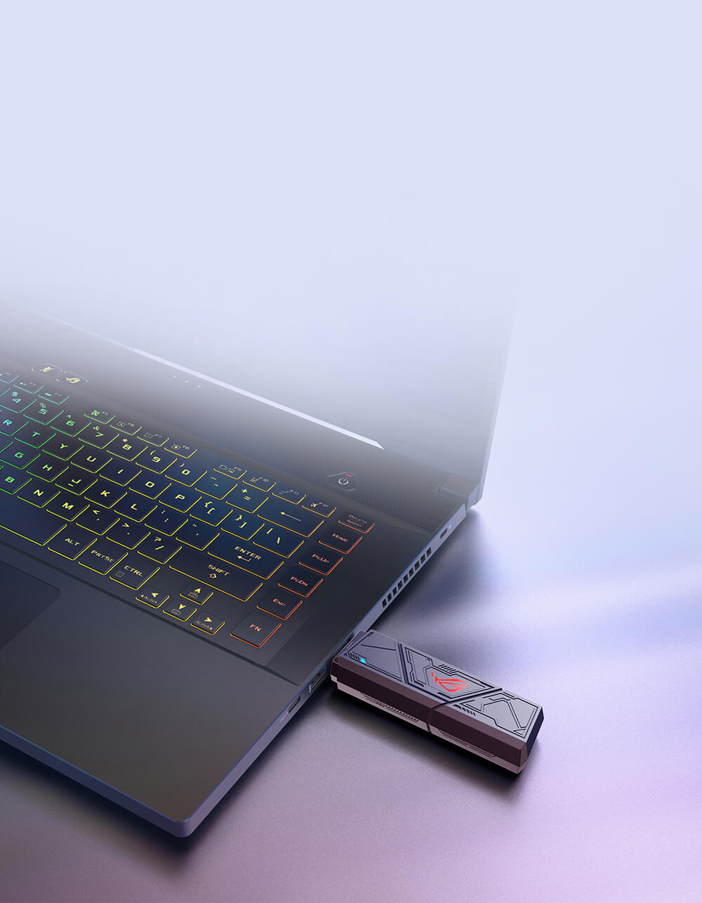 Elegancki laptop z klawiaturą RGB stoi na odblaskowej powierzchni, obok futurystycznego adaptera WiFi 7 USB z geometrycznymi wzorami i świecącym emblematem ROG