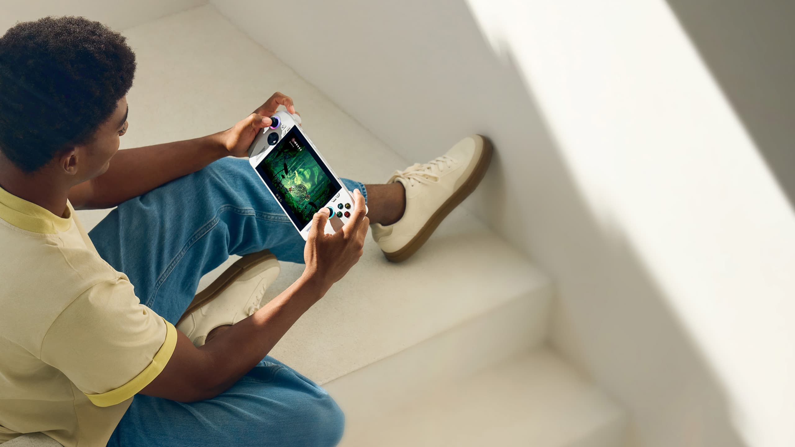 A person sitting on a staircase playing with an ROG Xbox Ally.