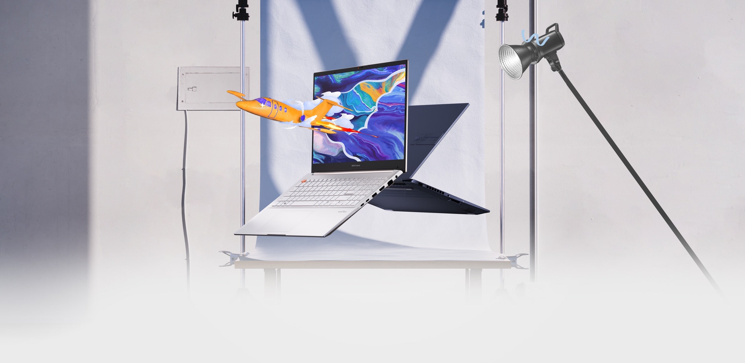 Hai chiếc laptop Vivobook Pro 15 OLED nhìn từ mặt trước và sau, một chiếc hiển thị hình ảnh một chiếc máy bay nổi bật trên hình ảnh nhiều màu sắc trên màn hình