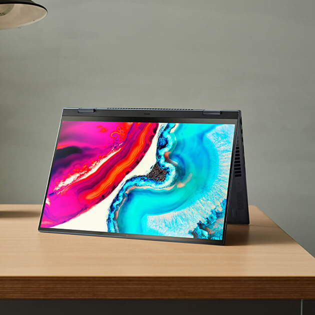 Ноутбук Zenbook стоит на столе рядом с выключенной лампой и чашкой. Экран ноутбука, представляющий собой OLED-дисплей ASUS Lumina, отображает яркие цвета: розово-красный с левой стороны и голубой с правой.