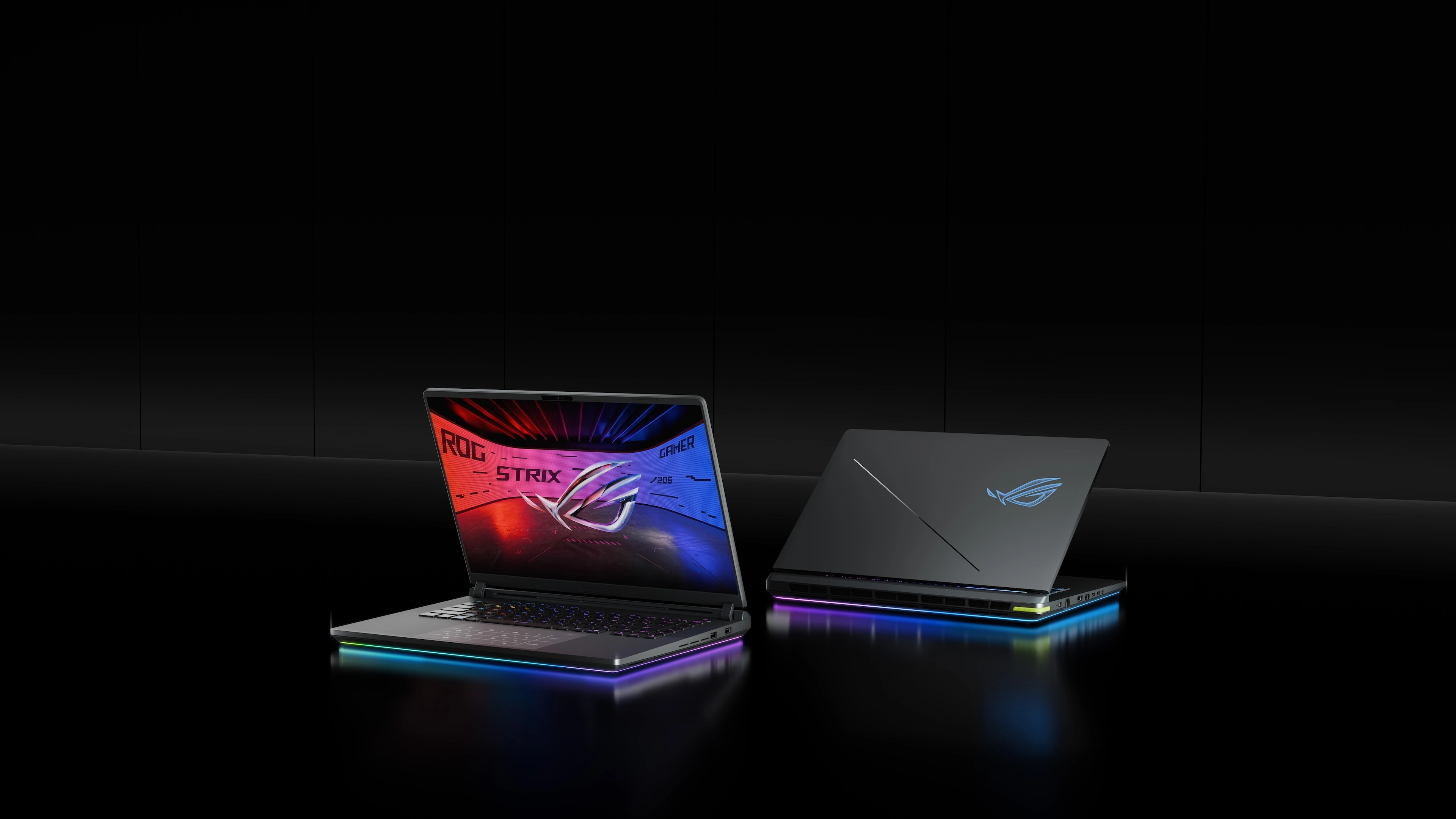 Two ROG Strix laptops on a table with the lids partially opened.