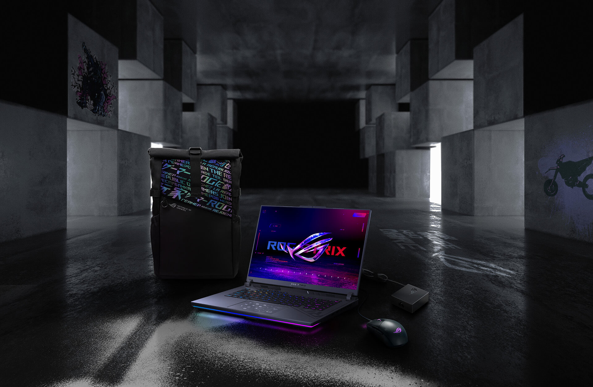 In an underground big space, from left to right; an ROG backpack, G16, ROG Strix Gladius III mouse, and 100W adapter.