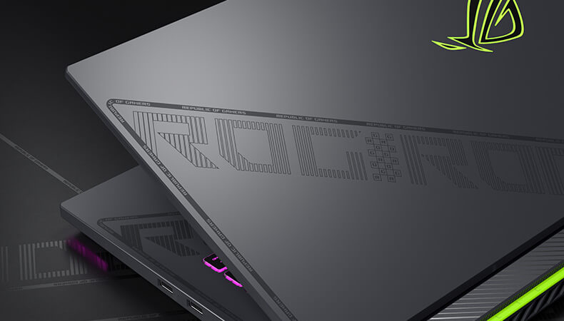 The laptop lid is shown, with the slash and ROG pattern design reflecting the surrounding light.