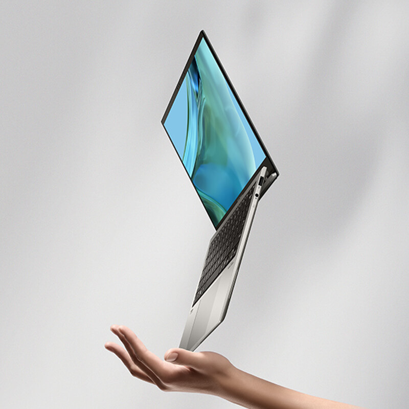 An open ASUS Zenbook S 13 OLED balancing on a hand on a corner of the laptop’s lower half.