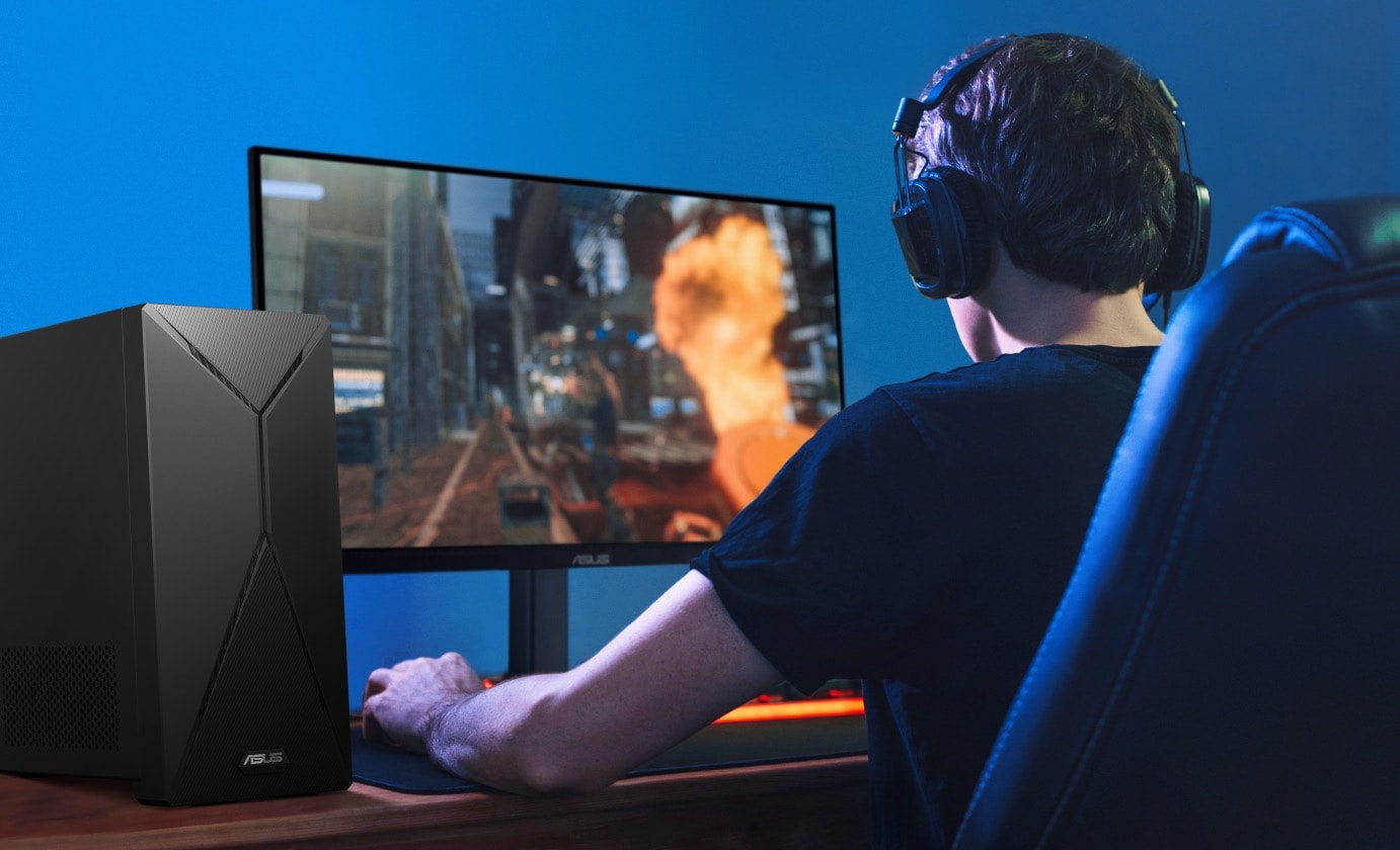 A man is playing video game through the monitor that is powered by an ASUS S501MER on his left-hand side.