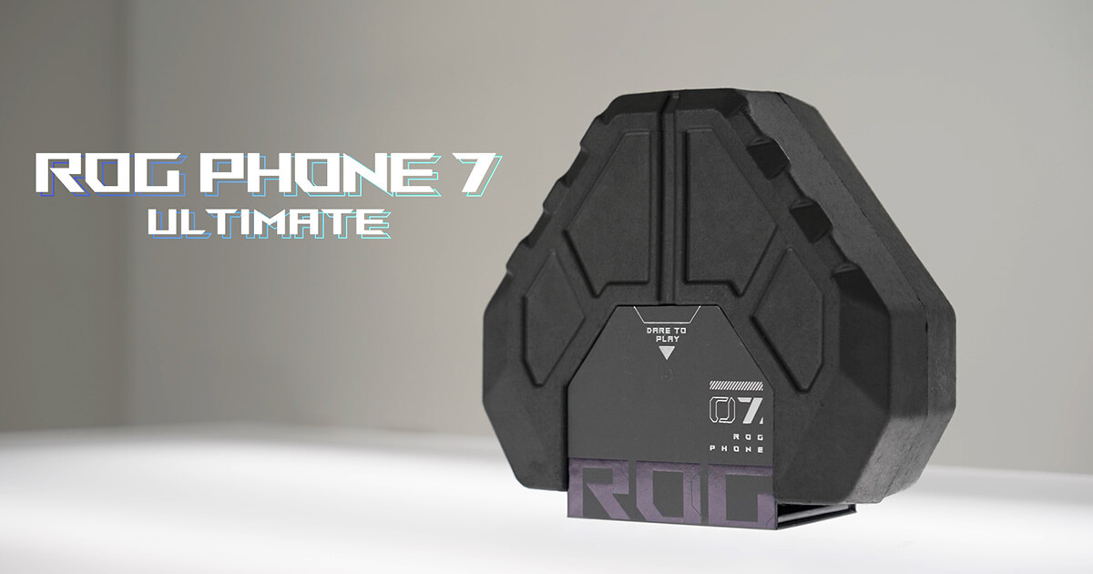There is an octagonal box of the ROG Phone 7 Ultimate showcased in the image. The box is placed on a softly lit surface by fluorescent light and the background is light grey. The product name is shown beside the box.