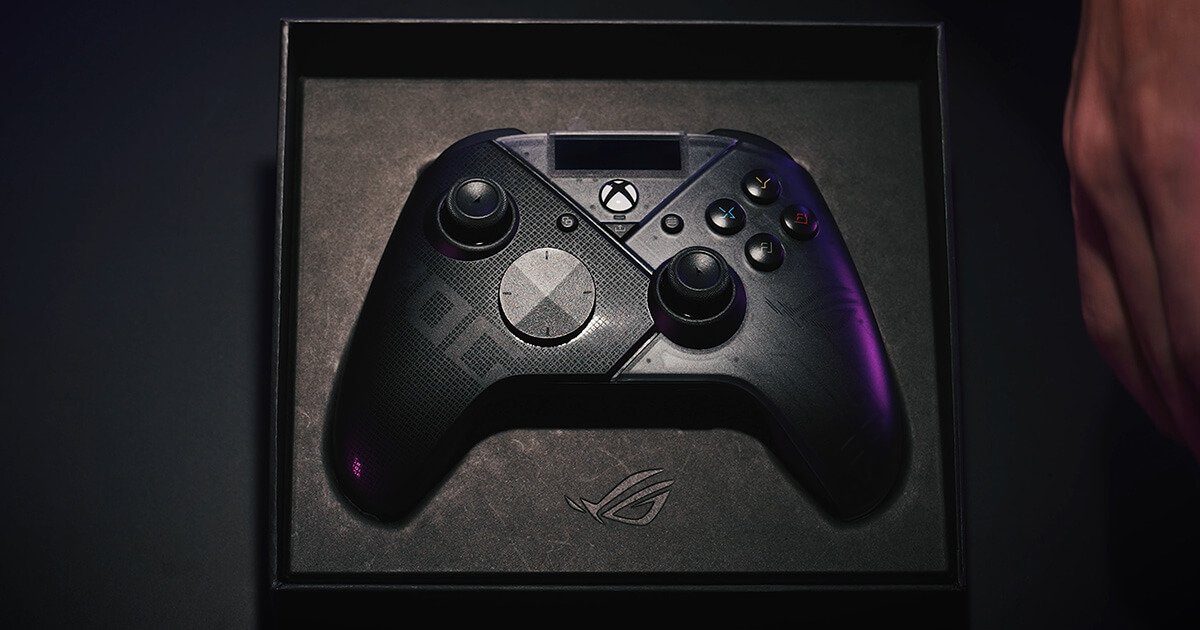 ROG Raikiri Pro, который применяется как контроллер для приставки Xbox, показан в центре изображения в черной бумажной коробке. В дополнение к освещению спереди, сбоку на устройство для придания стильного эффекта направлен луч фиолетового цвета.