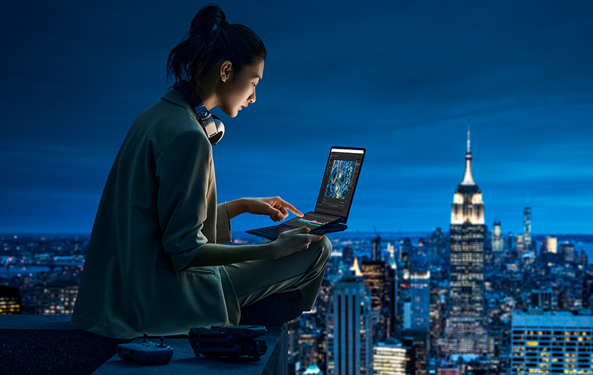A person uses her laptop on the roof at night, which can overlook the whole city view.