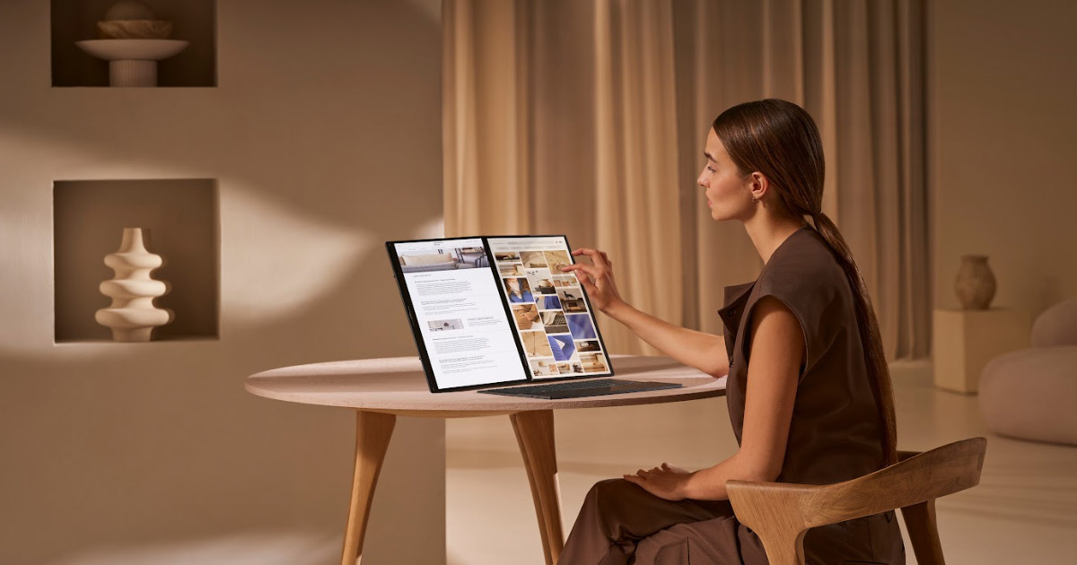 A woman sitting by a round table is scrolling through a webpage with her fingertip on her ASUS Zenbook DUO.
