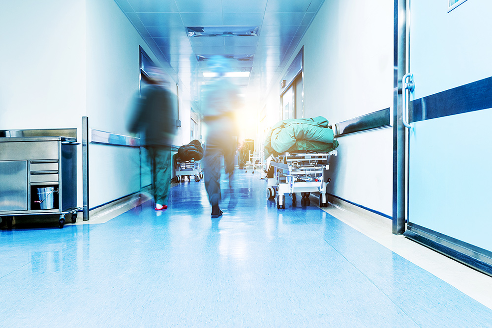 Outside emergency room hallway, doctors are walking fast