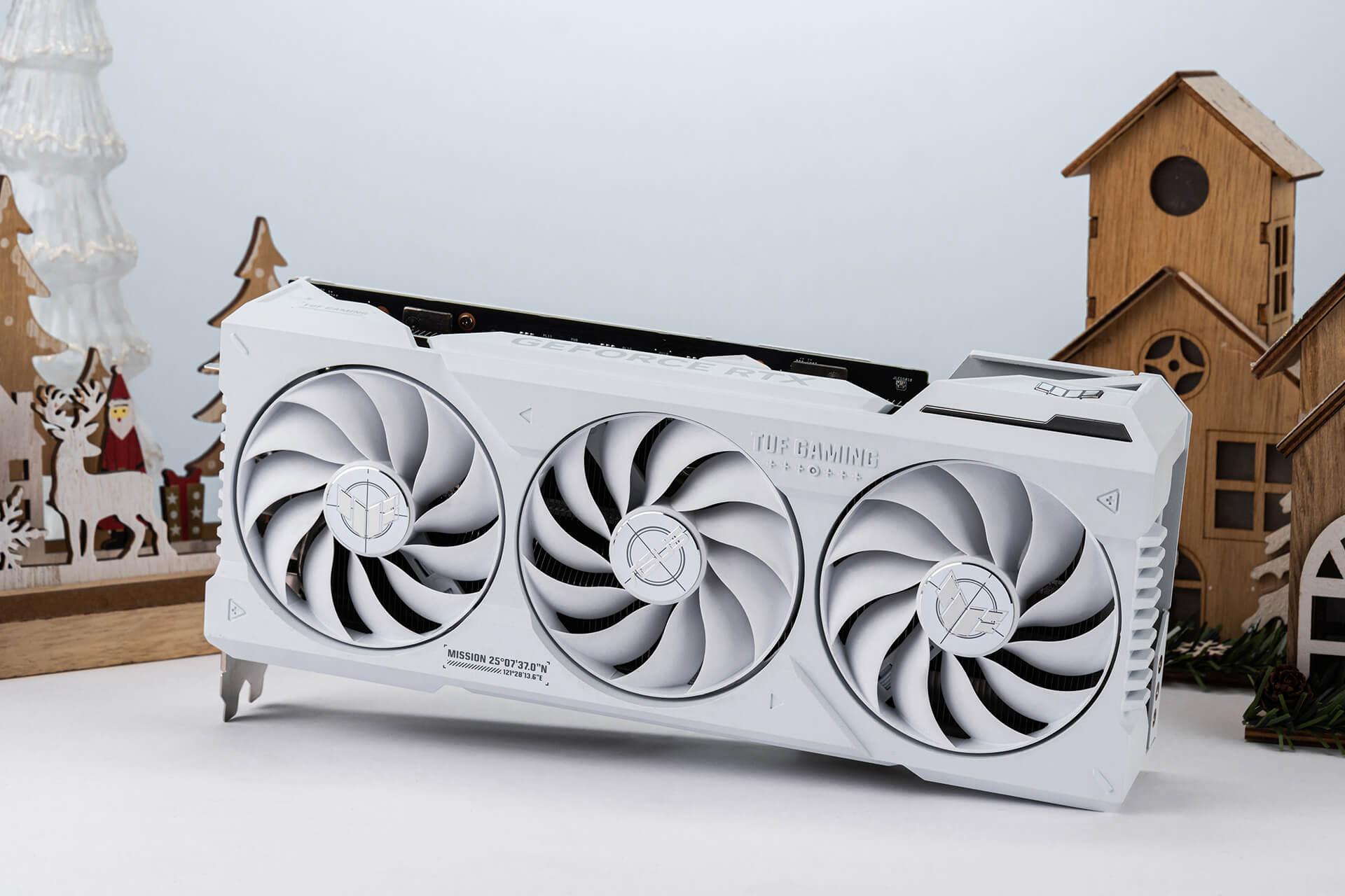 Una TUF Gaming GeForce RTX™ 4070 Ti SUPER BTF White Edition tumbada se sitúa en el centro con fondo navideño.