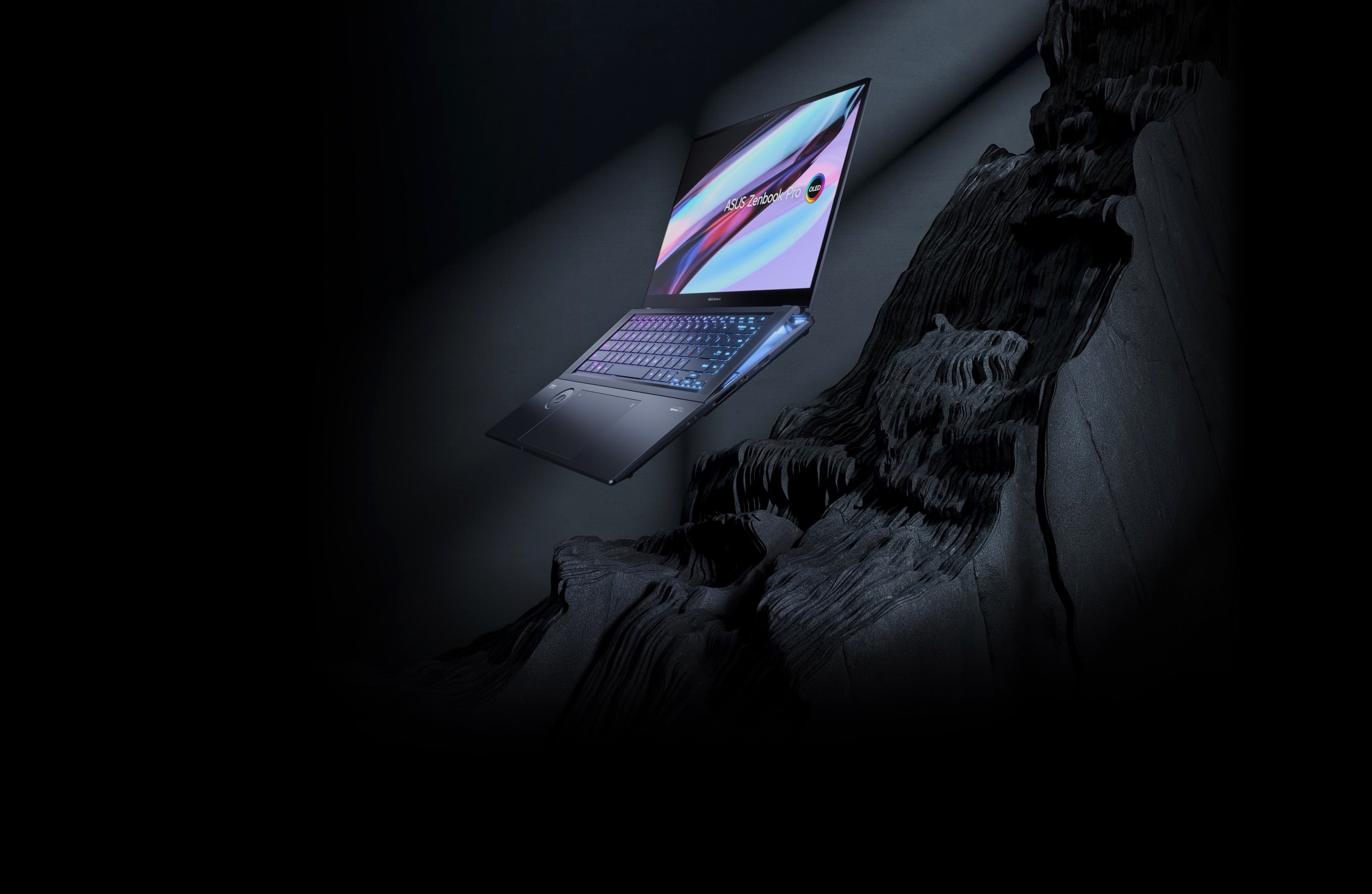 Zenbook Pro 16X OLED 以 120 度的角度展開，放置在一塊黑色岩石的表面上