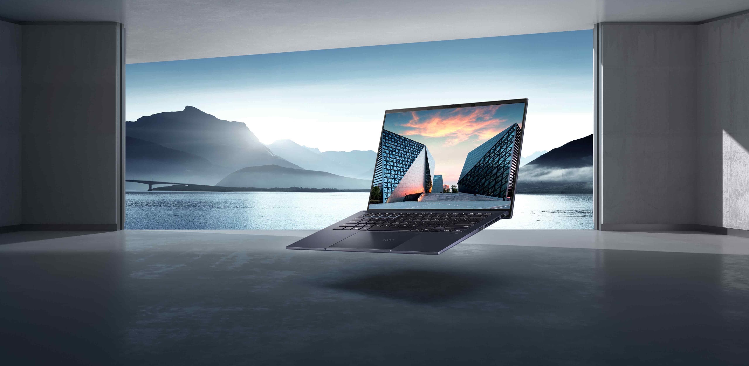 A front view of ExpertBook B9 floating in the air in front of mountains with trees and lake, while inside a cement building.