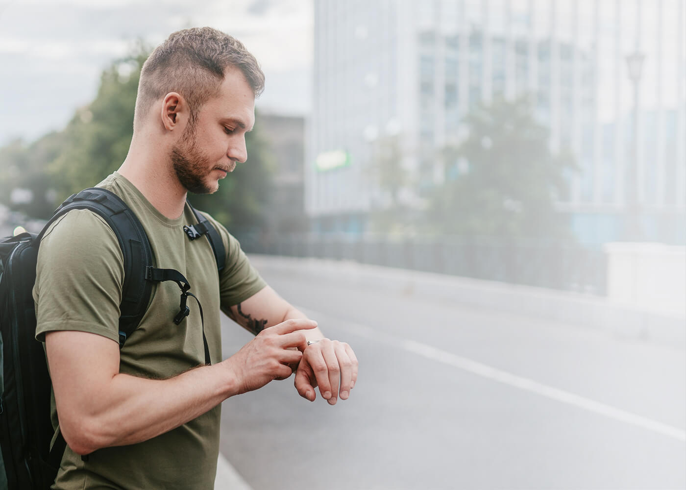 A man is standing on the street looking for direction with a smart phone showing map and a smart band with GPS function on