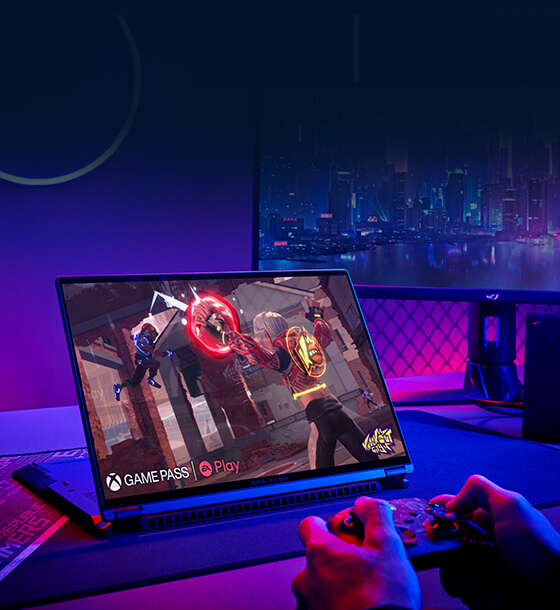 Hands hold a controller while a laptop displays gameplay of Knockout City.