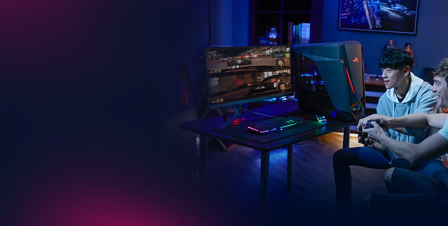 Two young men are enthusiastically playing a racing game on a dual-monitor setup connected to a ROG gaming PC