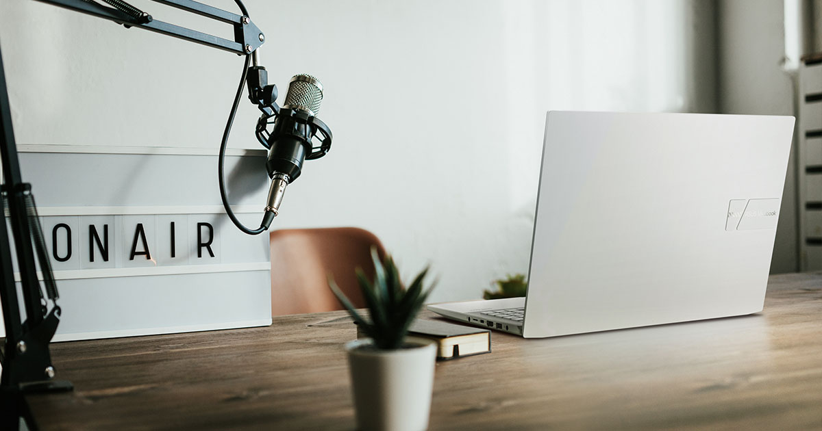 ASUS Vivobook Pro Creator Laptop on a desk in a minimalistic audio recording studio, with a microphone and an on-air sign next to it