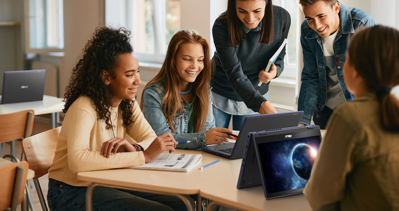 Groupe d'étudiants collaborant à un projet à l'aide d'ordinateurs portables dans une salle de classe.