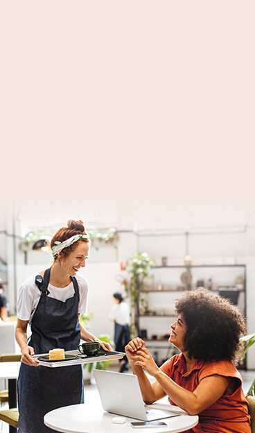 Un client utilise le WiFi d'un café tout en travaillant sur son ordinateur portable, tandis qu'un serveur souriant lui sert de la nourriture.