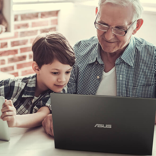 a senior user and a young child smiling while looking at an ASUS laptop’s screen together