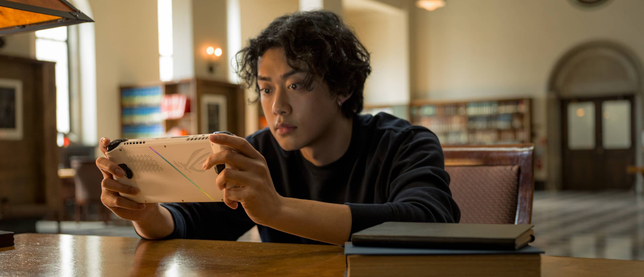 Person sitting in a library, playing with the Ally at a table.