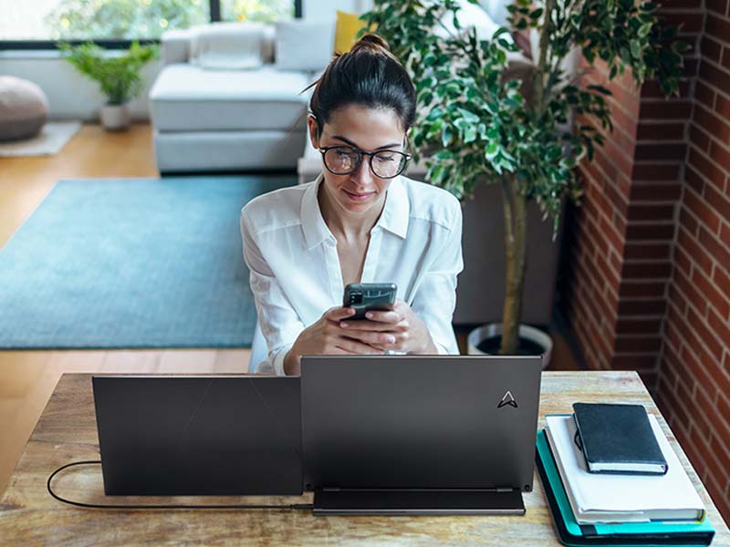 Een jonge professional beantwoordt haar smartphone en gebruikt de ZenScreen MB16QHG voor aansluiting op haar laptop om een extra scherm te hebben voor naadloze weergave