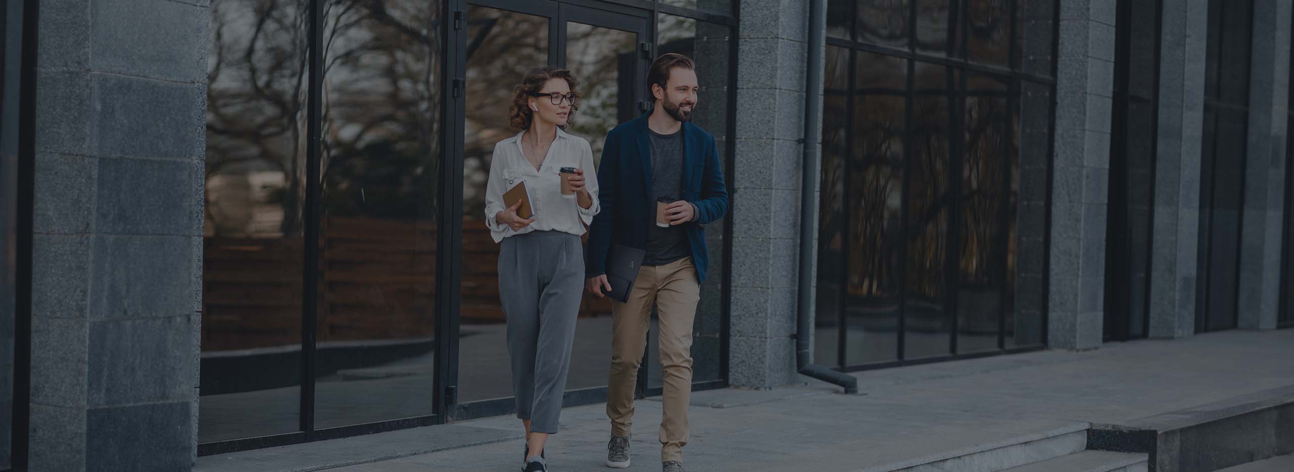 Stadsscène, met twee mensen op weg naar hun werk, de man draagt de draagbare ASUS ZenScreen-monitor moeiteloos in zijn linkerhand en houdt een drankje vast in zijn rechterhand