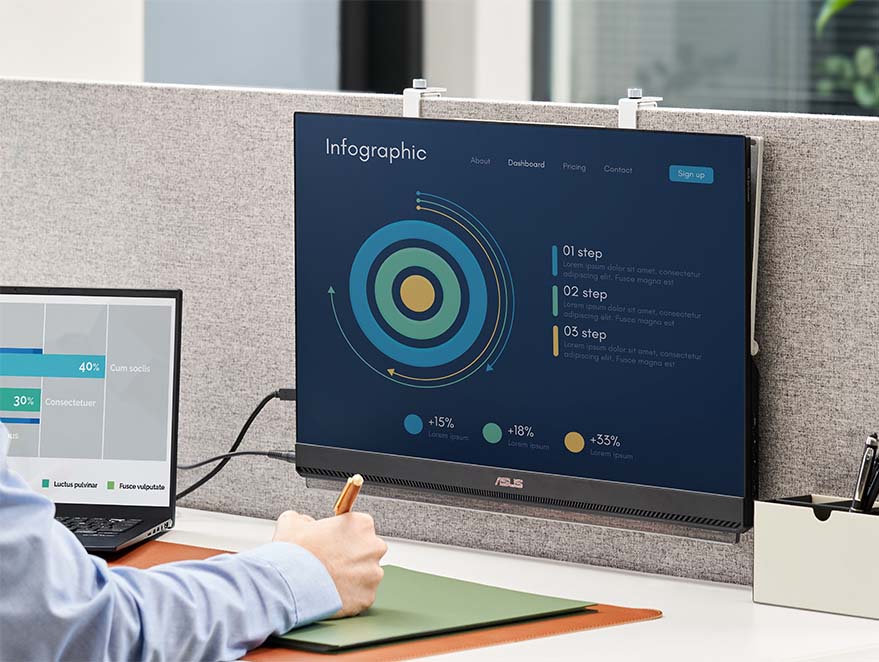 A man works in the open office with a laptop and ZenScreen MB249C portable monitor mount on the partition, space-saving on the desk