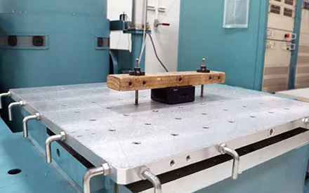 Industrial equipment in a lab with machinery, electrical panels, cables connected to a large cardboard box on a stand