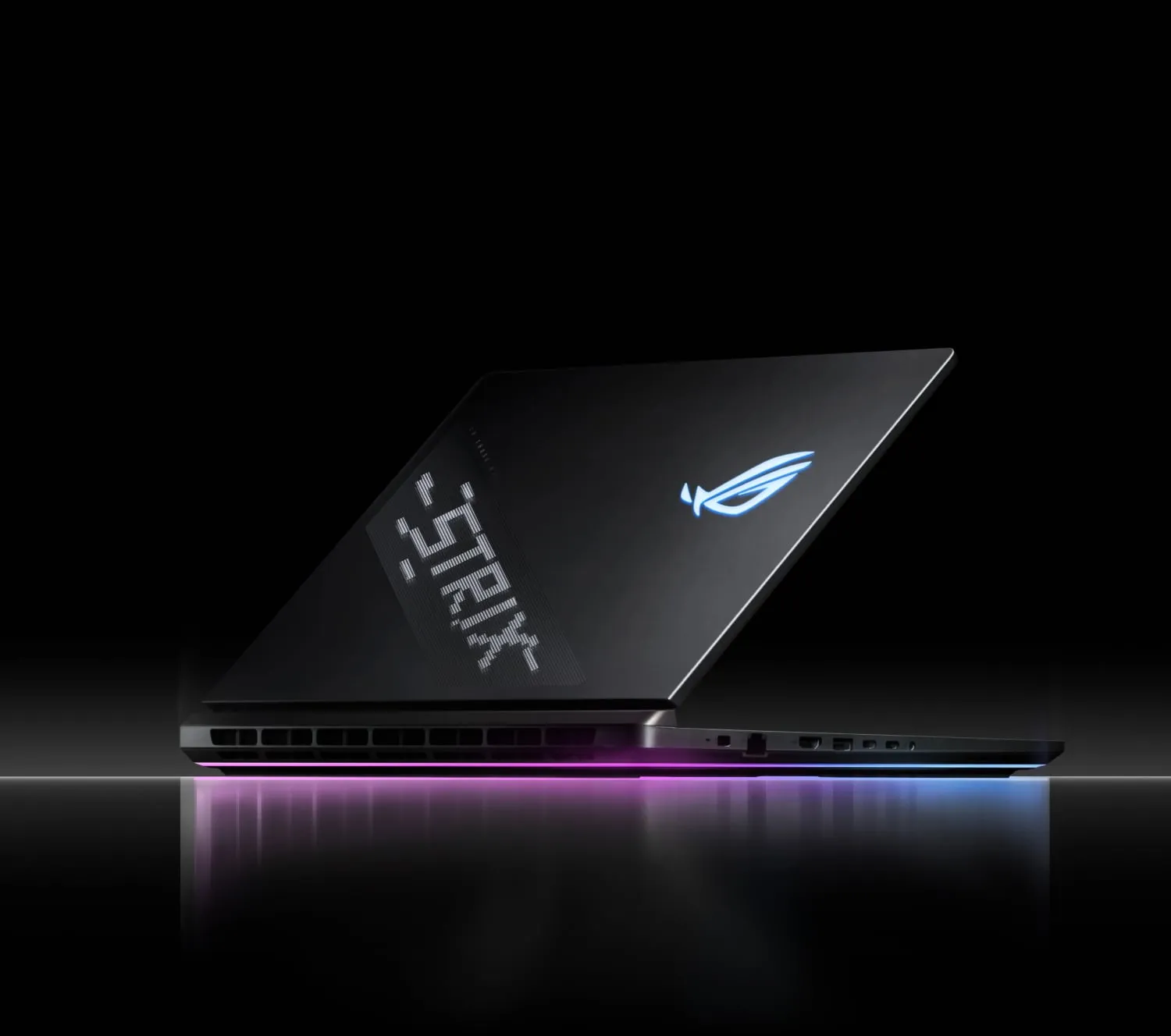 A Strix laptop sitting on a reflective surface with AniMe Vision and Full-surround RGB visible