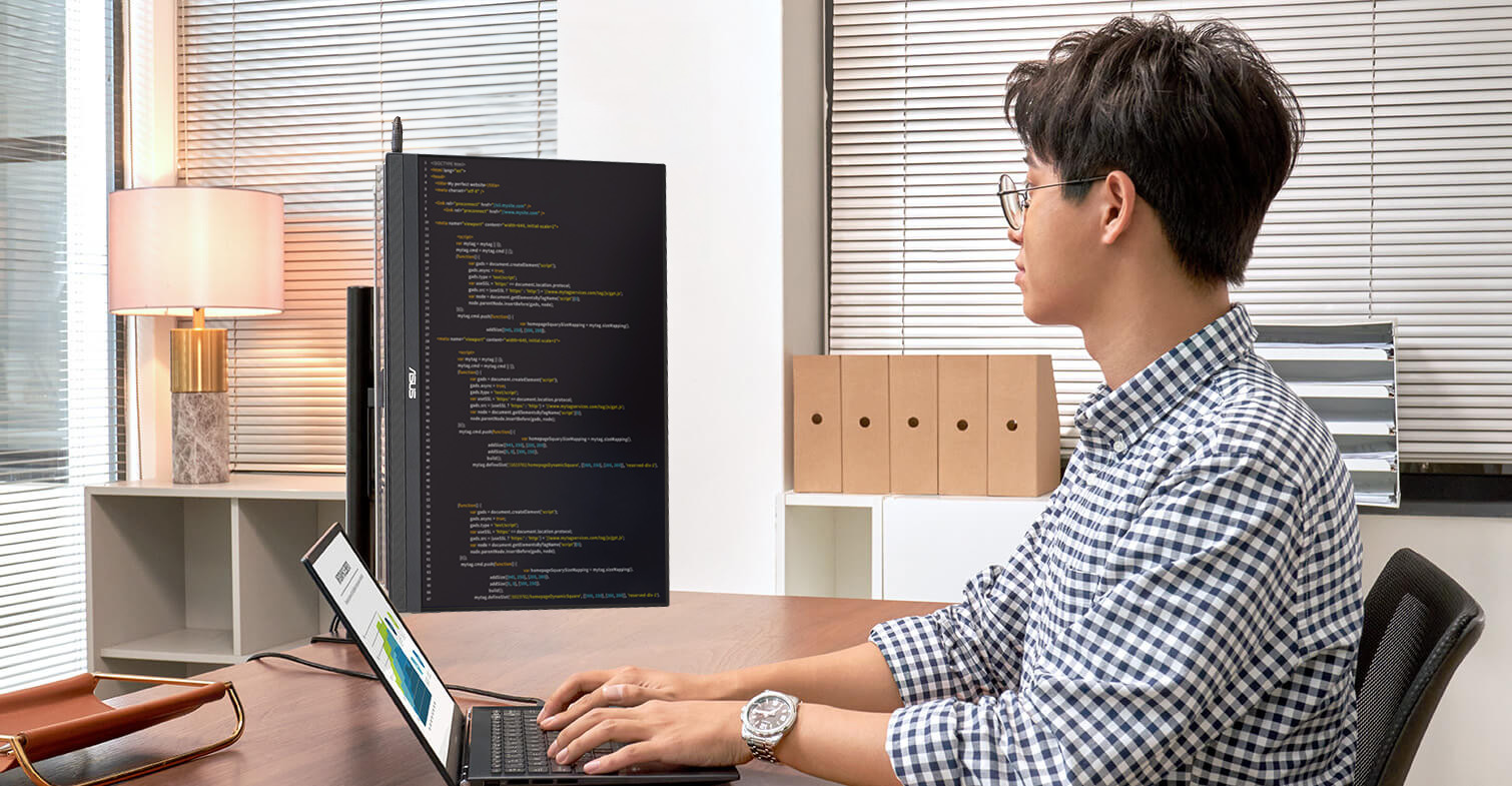 Een technicus werkt op kantoor met een laptop en de ZenScreen MB229CF in portretstand