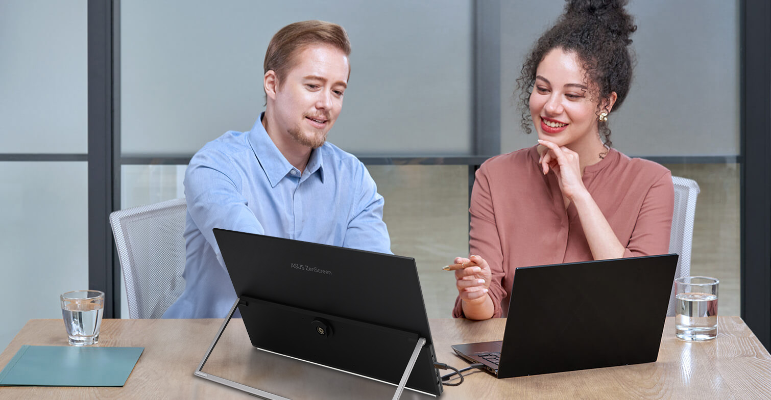 Unos compañeros discuten en una oficina compartida utilizando un portátil y el ZenScreen MB29CF
