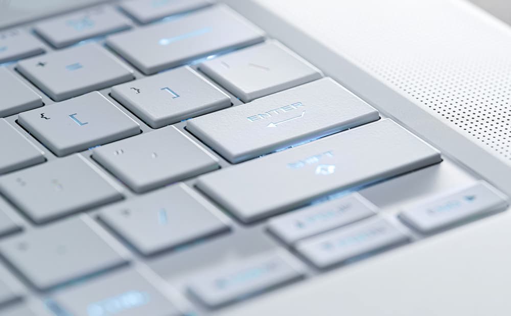 An extreme close up of a Platinum White Zephyrus G16’s keyboard, with emphasis on the arrow keys.