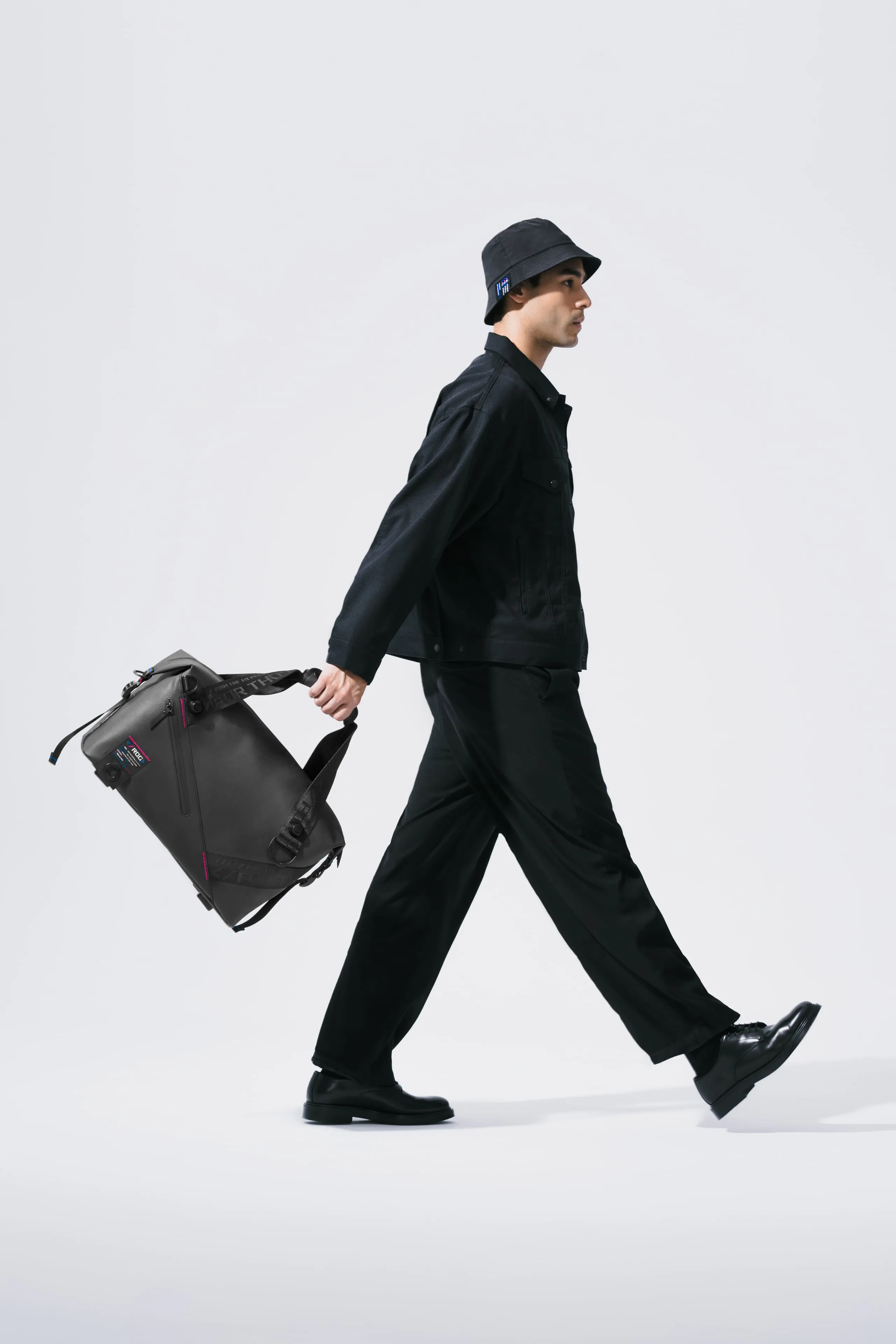 Man in midstride, carrying an ROG SLASH Duffle Bag by hand behind him