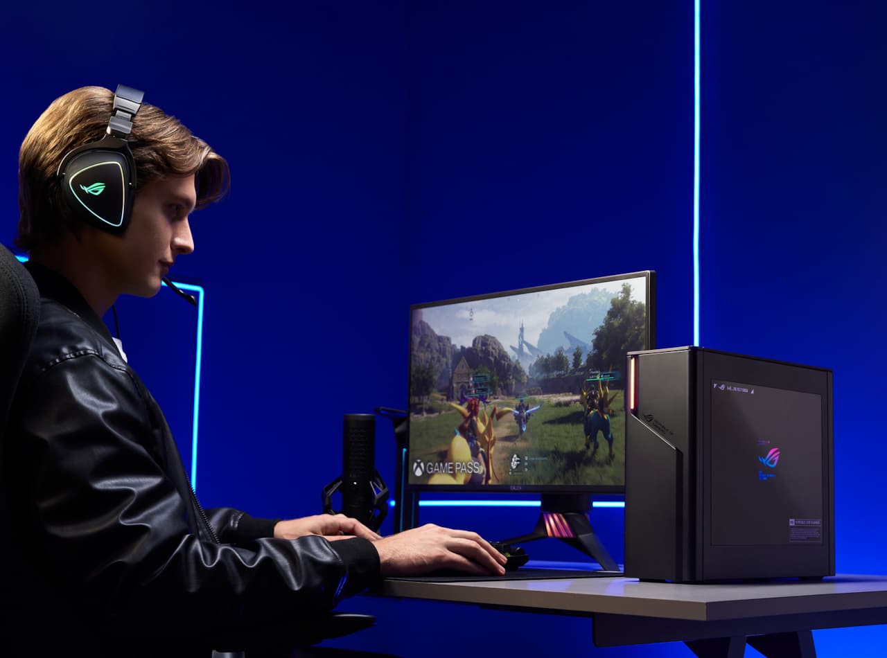 A person sitting at a desk and using an ROG desktop while wearing a headset.