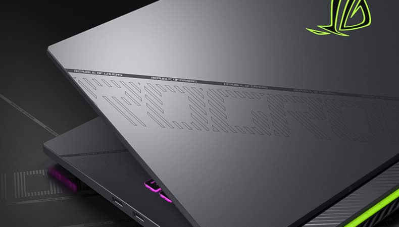 Nắp laptop được hiển thị với thiết kế họa tiết ROG và dấu gạch chéo phản chiếu ánh sáng xung quanh.