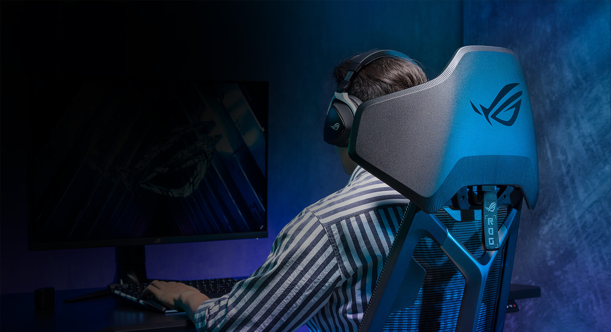 Pokazany w widoku pod kątem mężczyzna grający na komputerze desktopowym, siedzący na fotelu gamingowym ROG Destrier Ergo